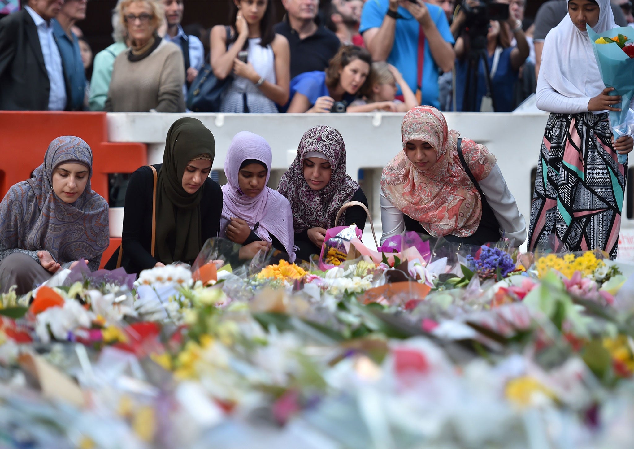 Young Muslim women lay flowers at a makeshift memorial near the scene of a fatal siege in the heart of Sydney's financial district on December 16, 2014.