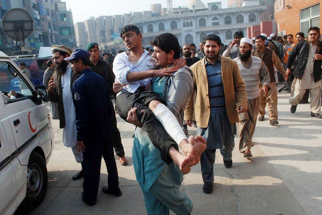 A man carries a student, who was injured during an attack by Taliban gunmen on the Army Public School, after he received treatment at a hospital in Peshawar