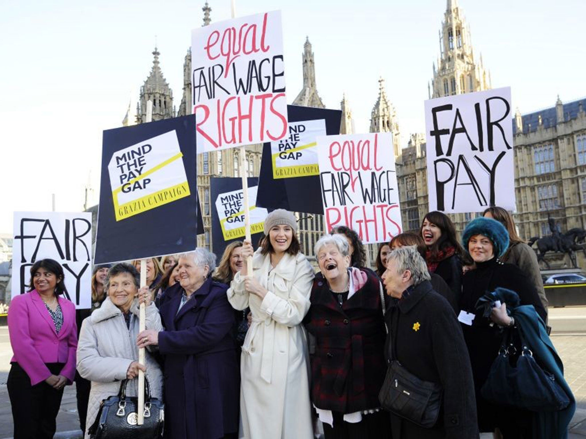 Gemma Arterton (C) holds a placard outside the Houses of Parliament to mark the tabling of the motion on equal pay
