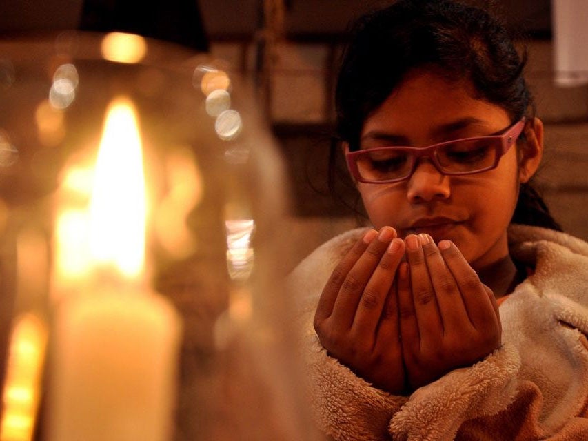 A girl prays during a candle lit vigil for the victims of the Taliban attack