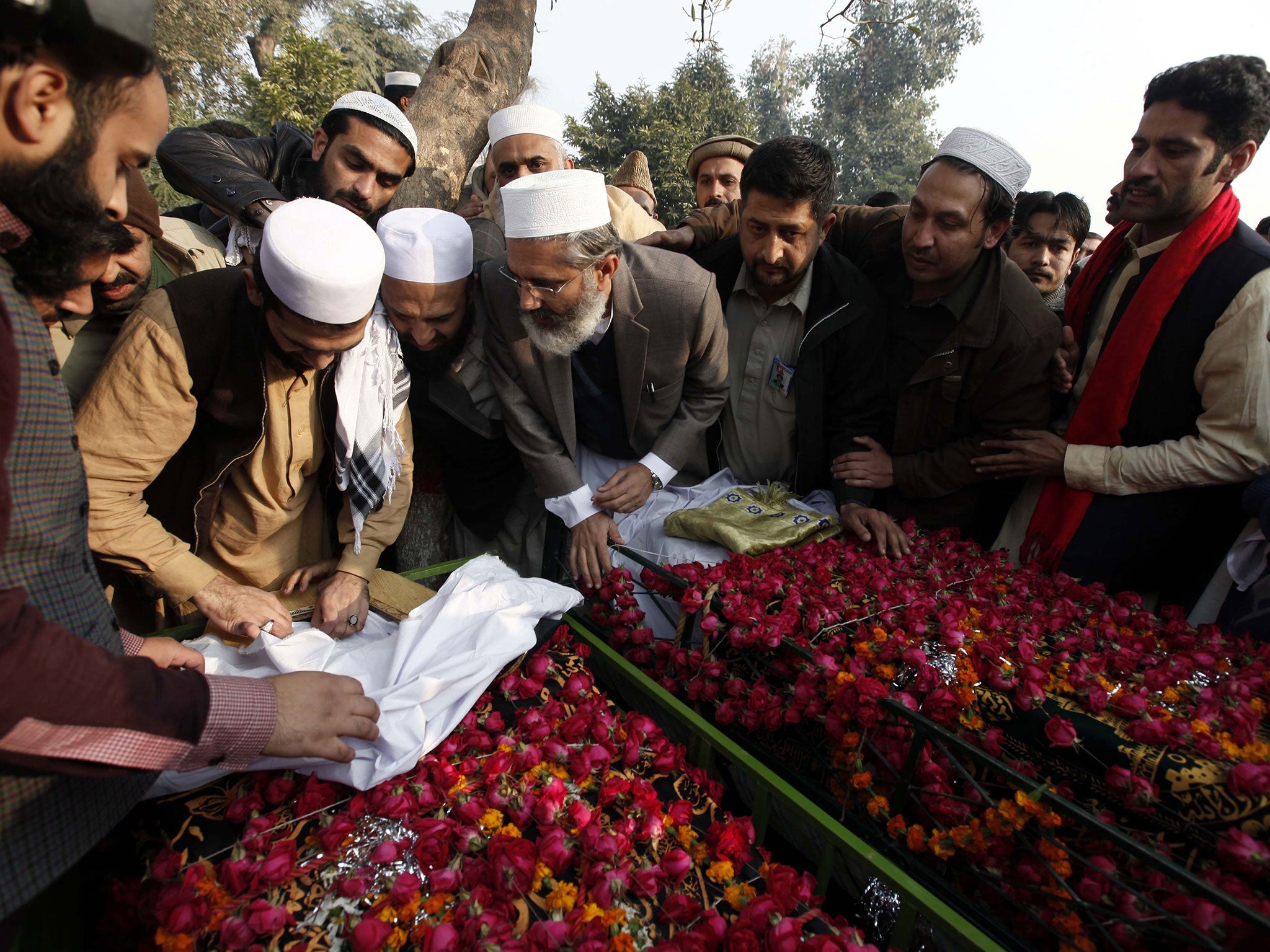 People attending the funeral of students killed in the Taliban attack on a school prepare for their burial in Peshawar, Pakistan, on Wednesday, December 17