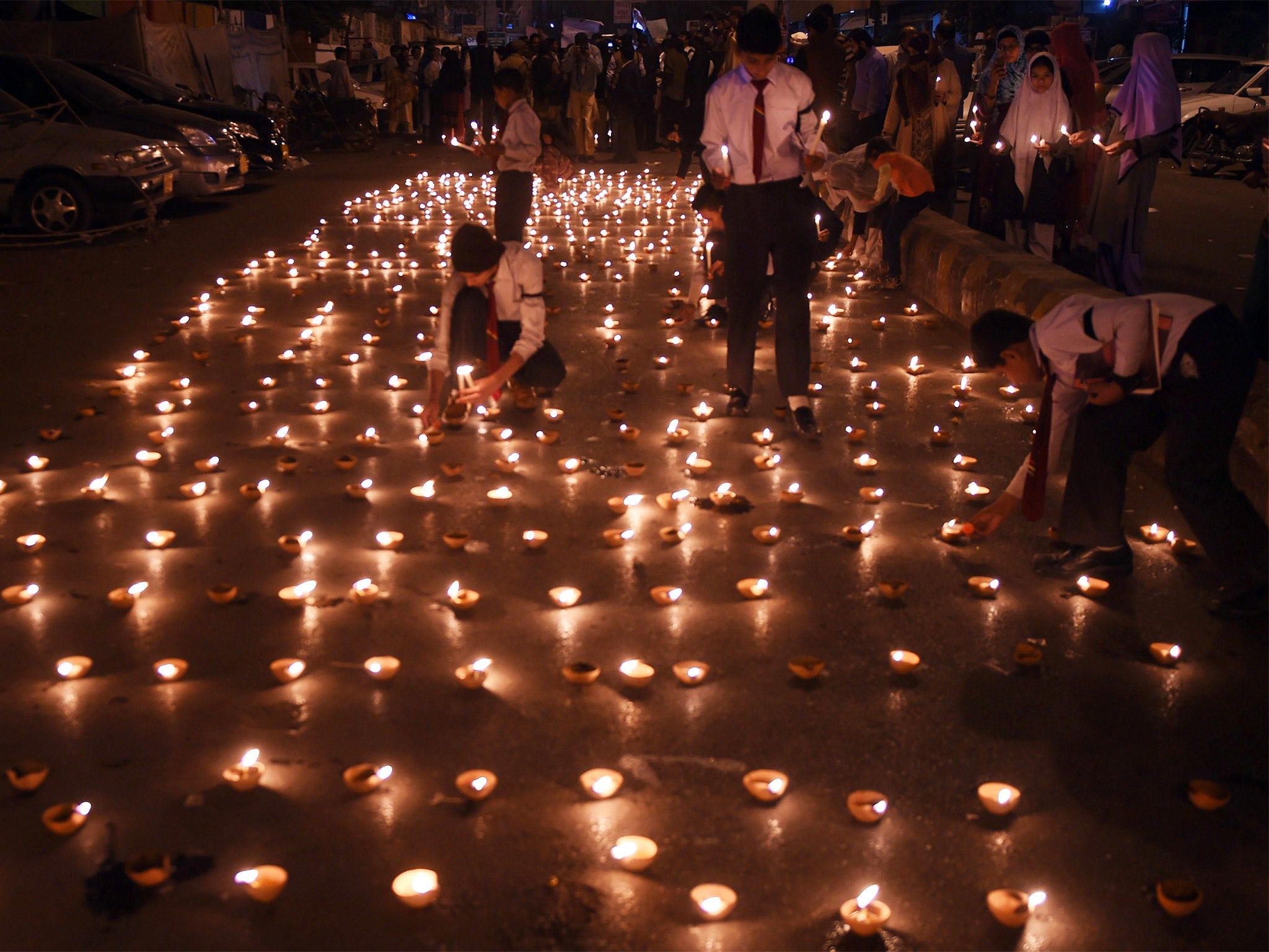 Pakistani students in Karachi light earthen lamps for the victims of the attack in Peshawar