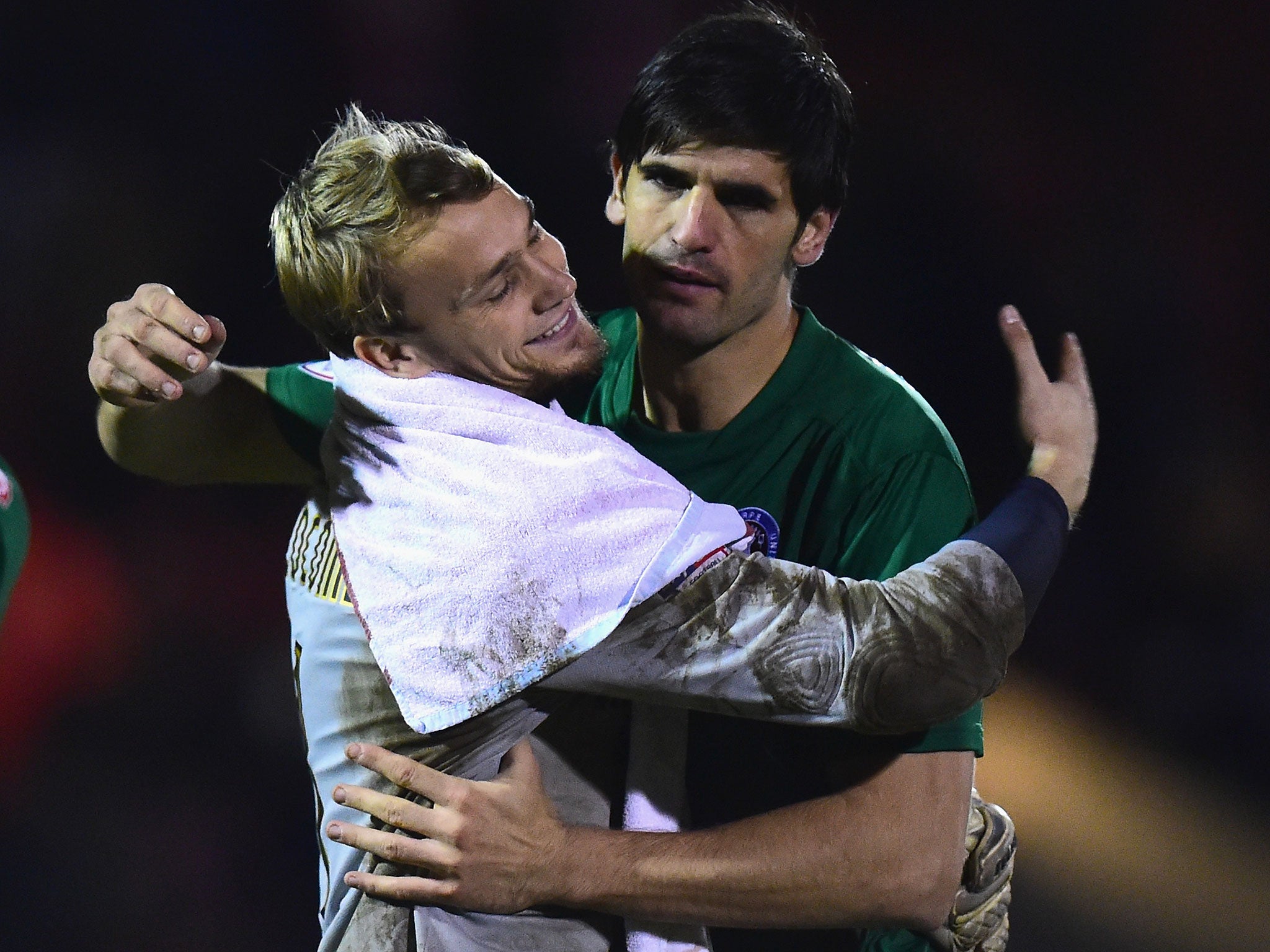 Scunthorpe goalkeeper Sam Slocombe (left) is congratulated by winning penalty taker Miguel Llera (right)