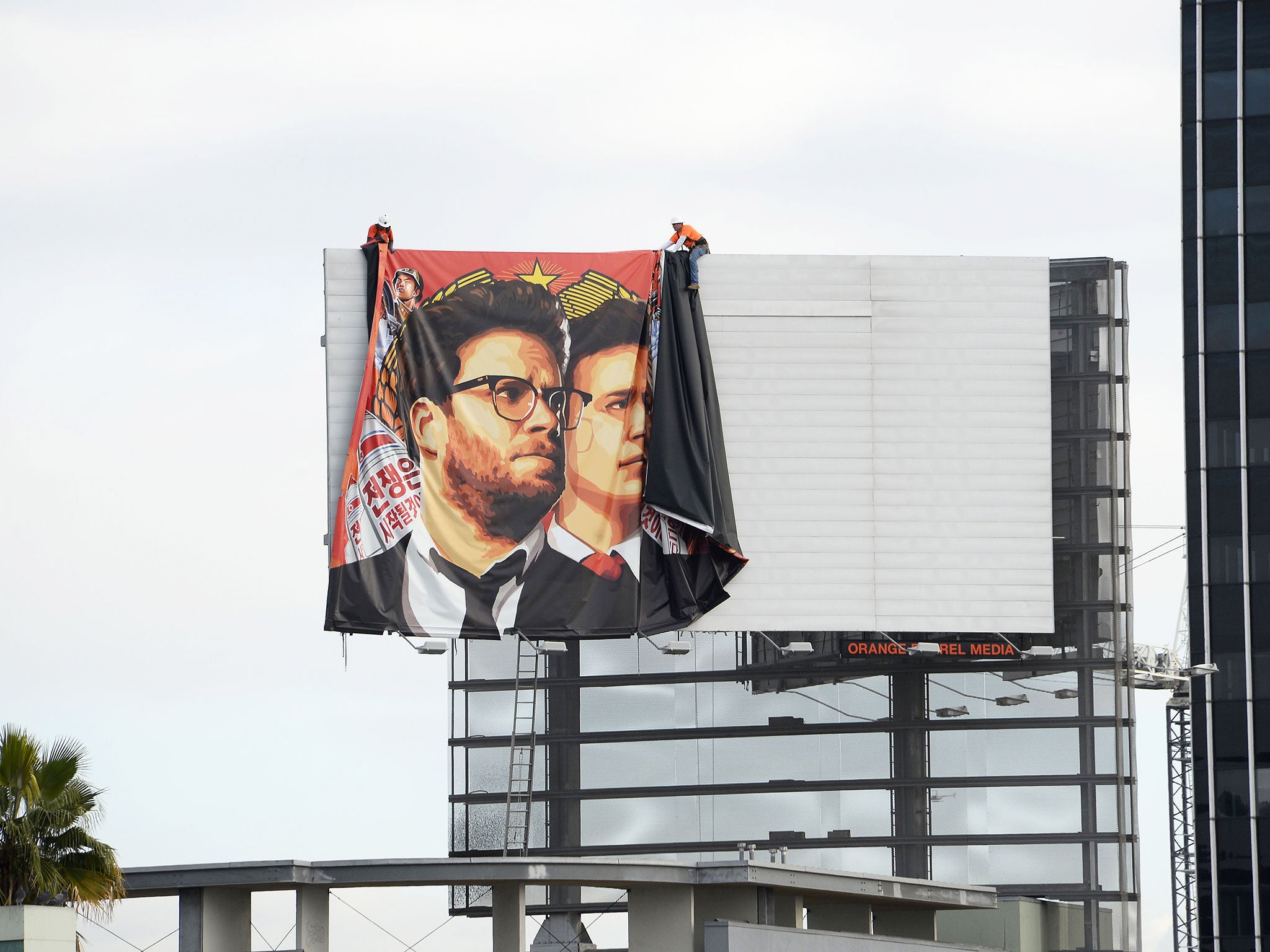 Workers remove a poster-banner for The Interview from a billboard in Hollywood