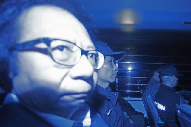 In this photo taken through a tinted glass, Thomas Kwok, left, co-chairman of Hong Kong developer Sun Hung Kai Properties, is escorted by staff members from Hong Kong Correctional Services inside a van outside the High Court in Hong Kong