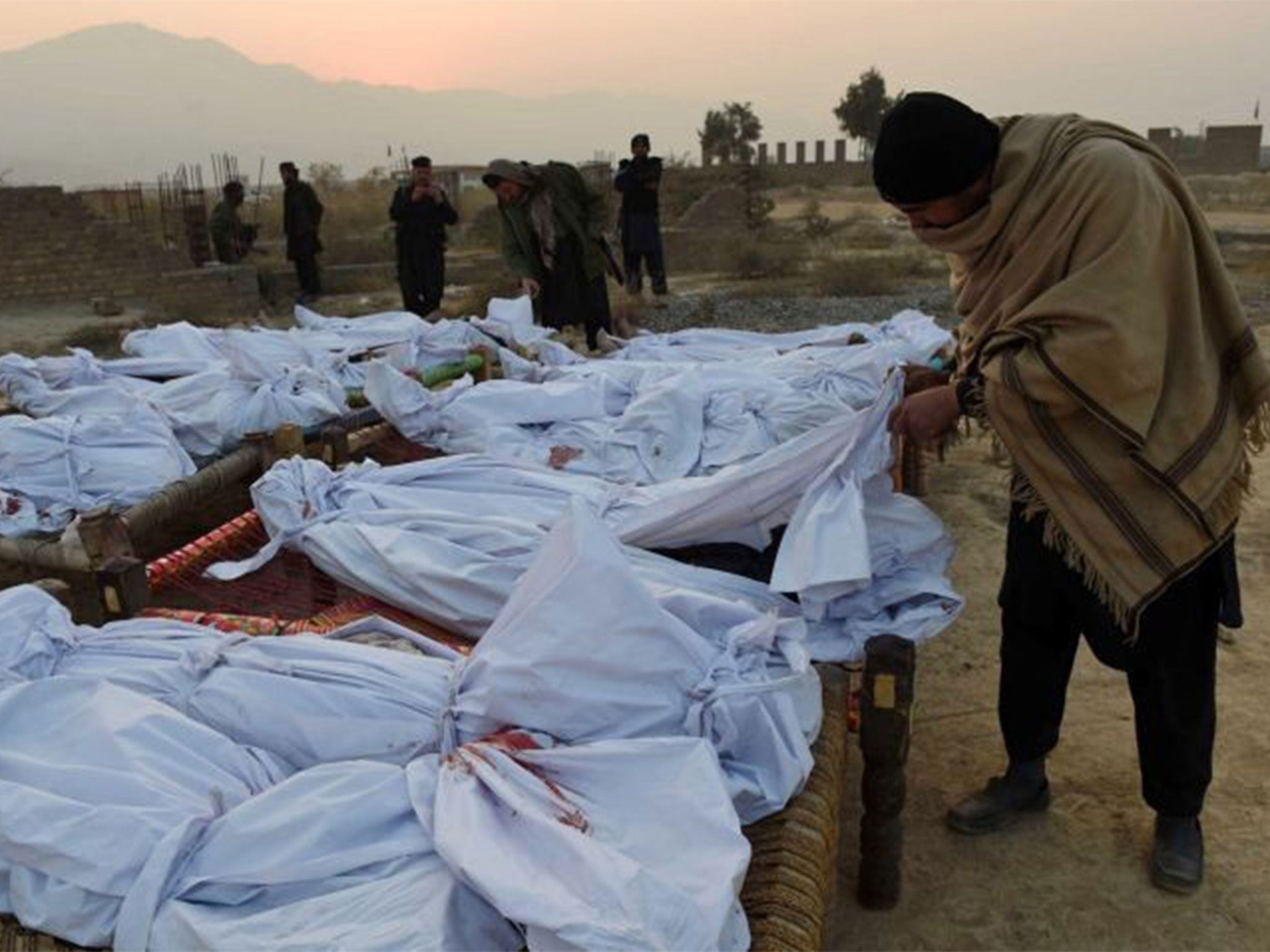 A Pakistani Frontier Corps member looks at gathered bodies of militants killed in a military operation in Tirah, near the Pakistan-Afghanistan border, on 19 December as operations against insurgents intensify in the wake of the Peshawar school massacre