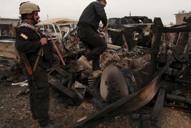 Kurdish Peshmerga fighters stand near burning vehicles during a suicide attack carried out by the Islamic State group in Kesarej village, south of Zumar, Nineveh province on 18 December 2014. Kurdish peshmerga fighters have fought their way to Iraq's Sinj