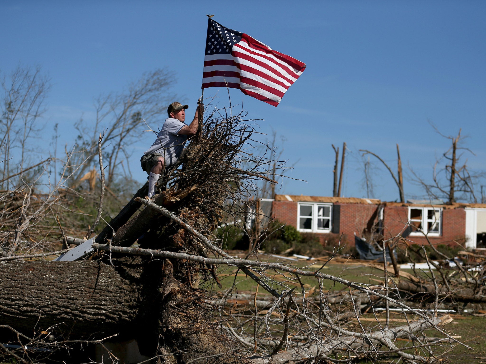 A man places an American flag in front of what is left of his brothers house after it was destroyed when a tornado hit in Louisville, Mississippi