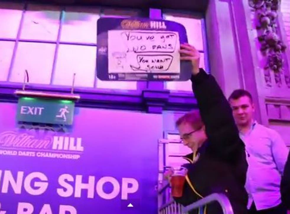 The Wealdstone Raider holds up a placard reading "You've got no fans. You want some?" at the World Darts Championship