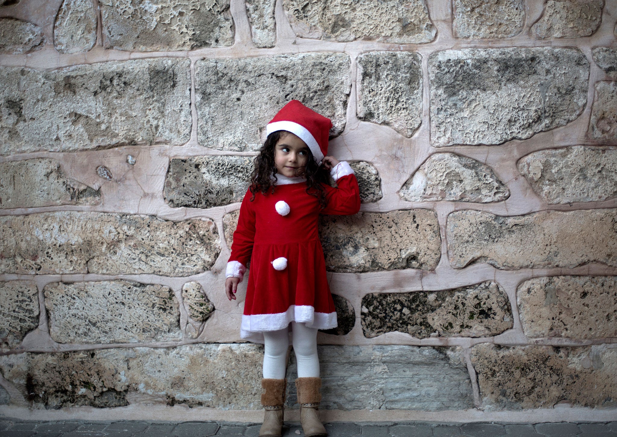 A Palestinian Greek Orthodox Christian girl dressed in Santa Claus stands outside the Saint Porfirios church in Gaza City on December 22, 2013