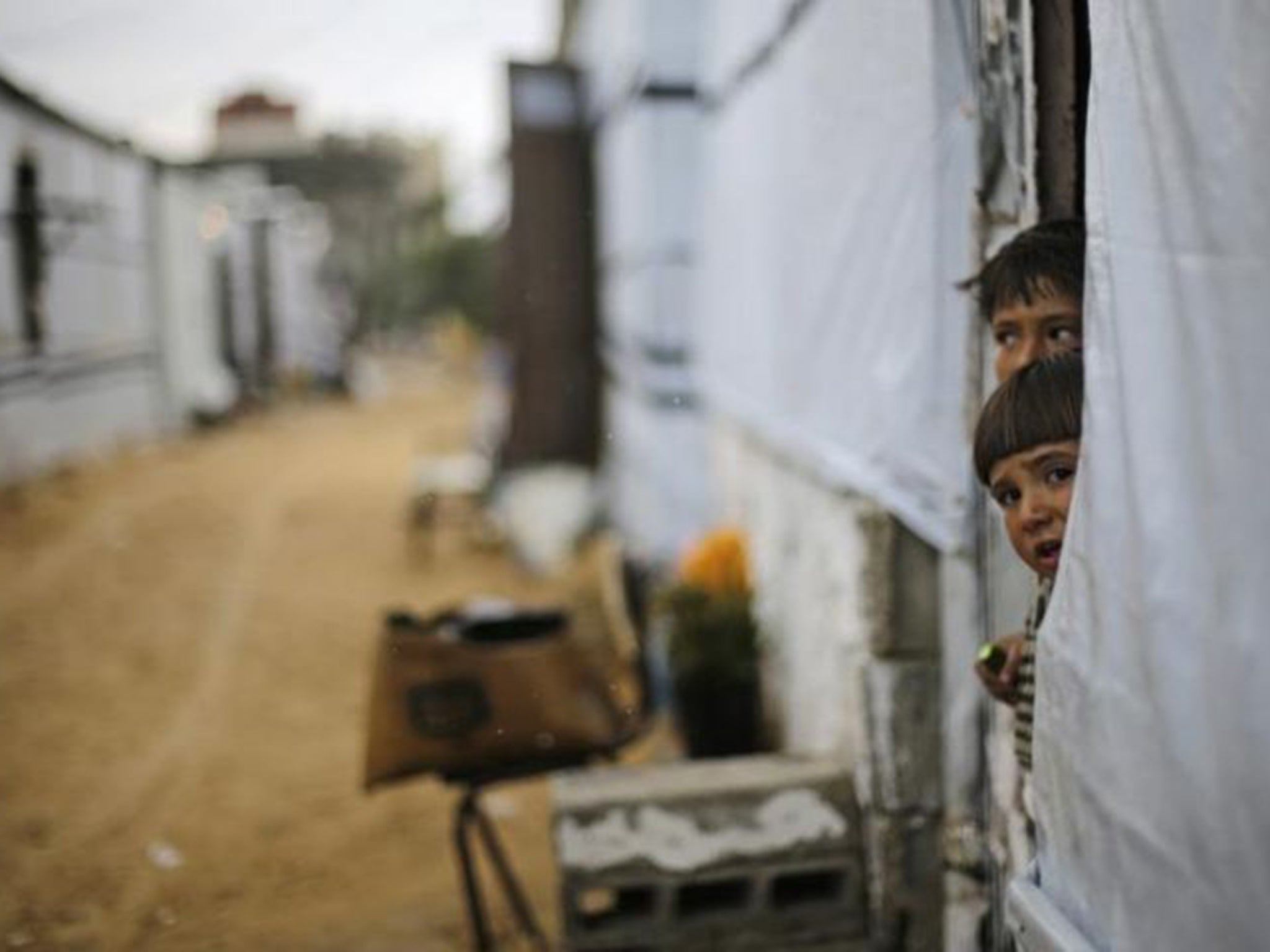 Palestinian children look out from their temporary home