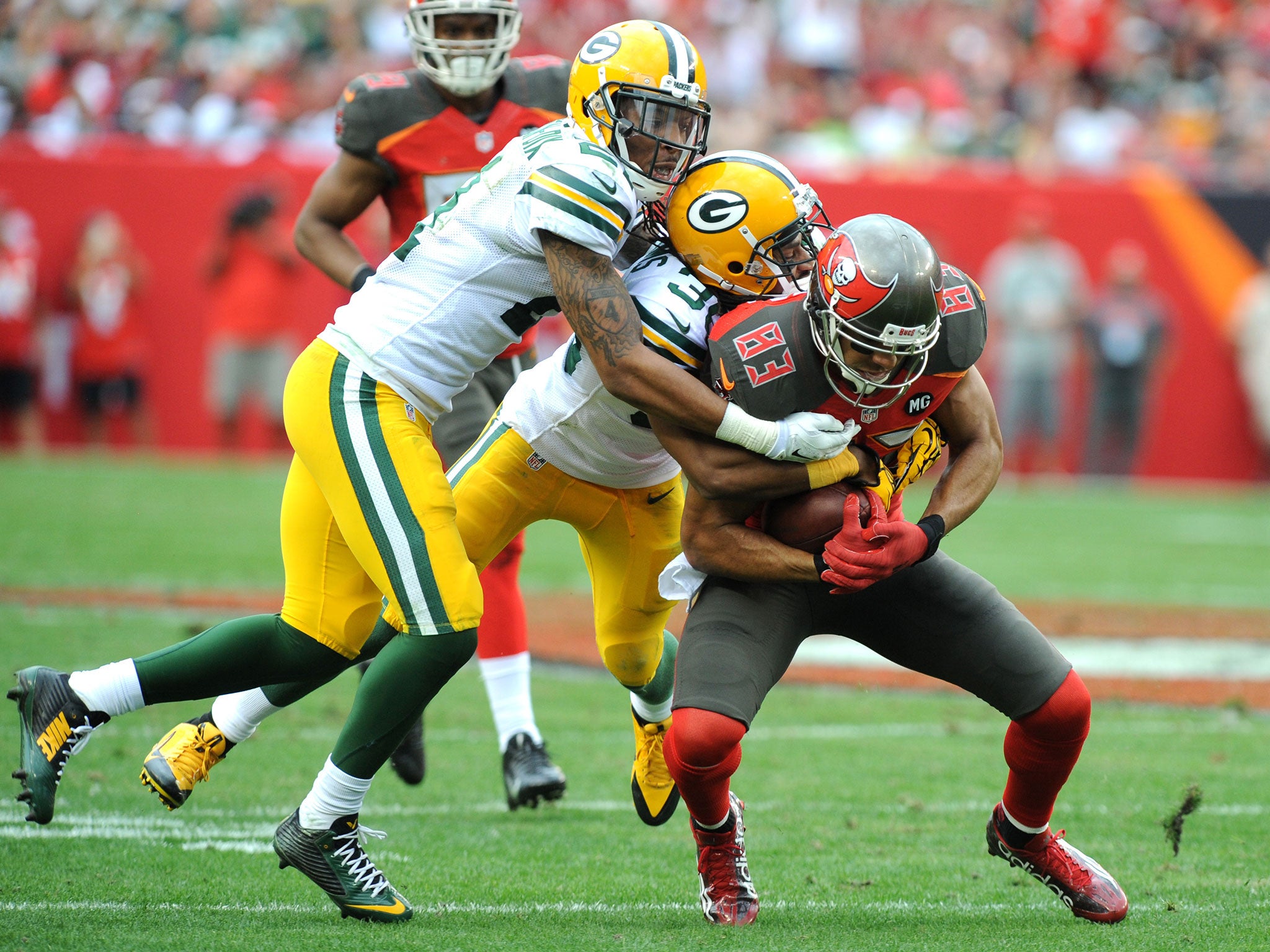 Ha Ha Clinton-Dix (L) of the Green Bay Packers and corner-back Tramon Williams (C) of the Green Bay Packers tackle wide receiver Vincent Jackson (R)