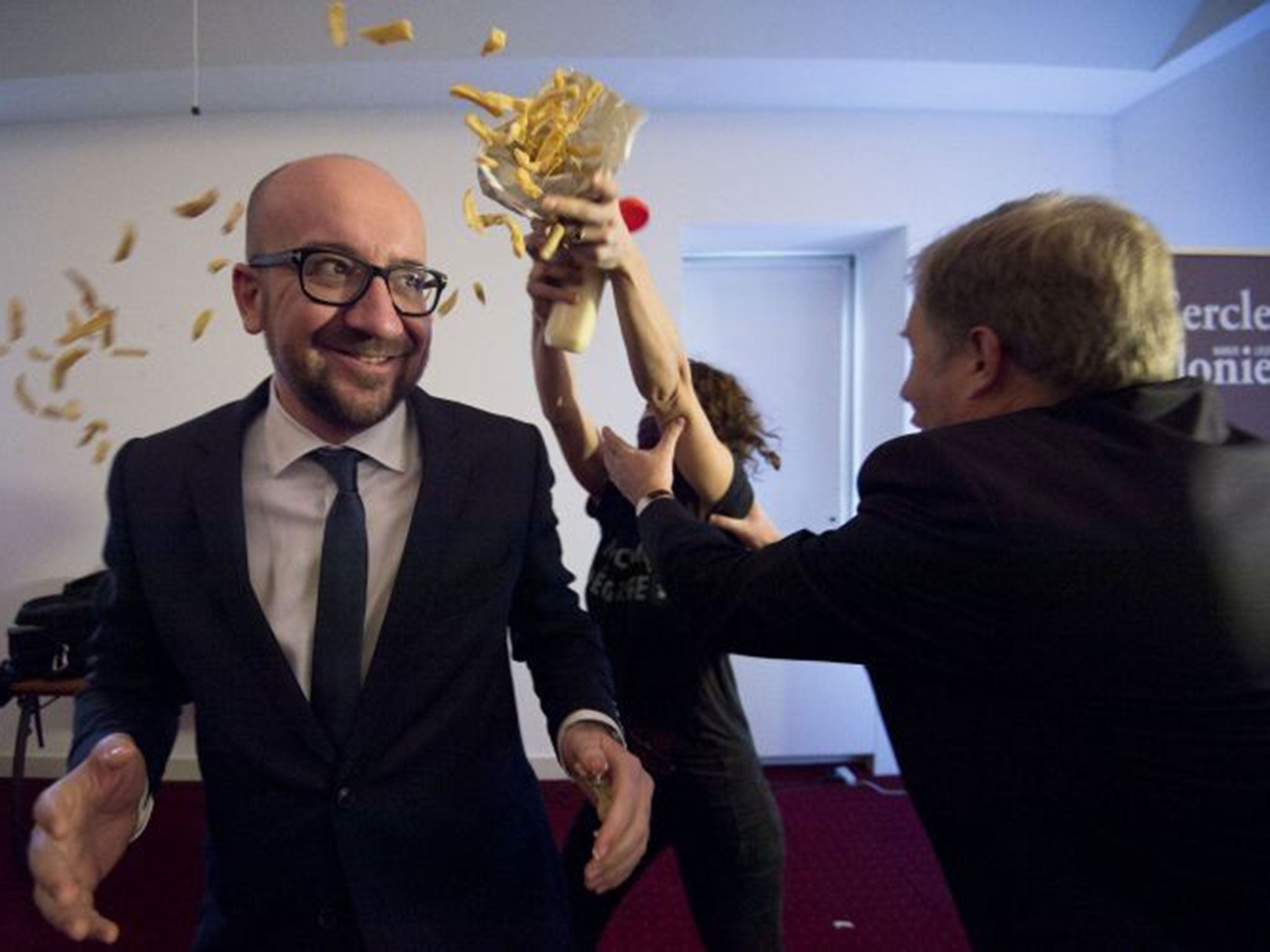 Belgian Prime Minister Charles Michel (L) reacts as activists throw fries and mayonnaise on him during an anti-government protest