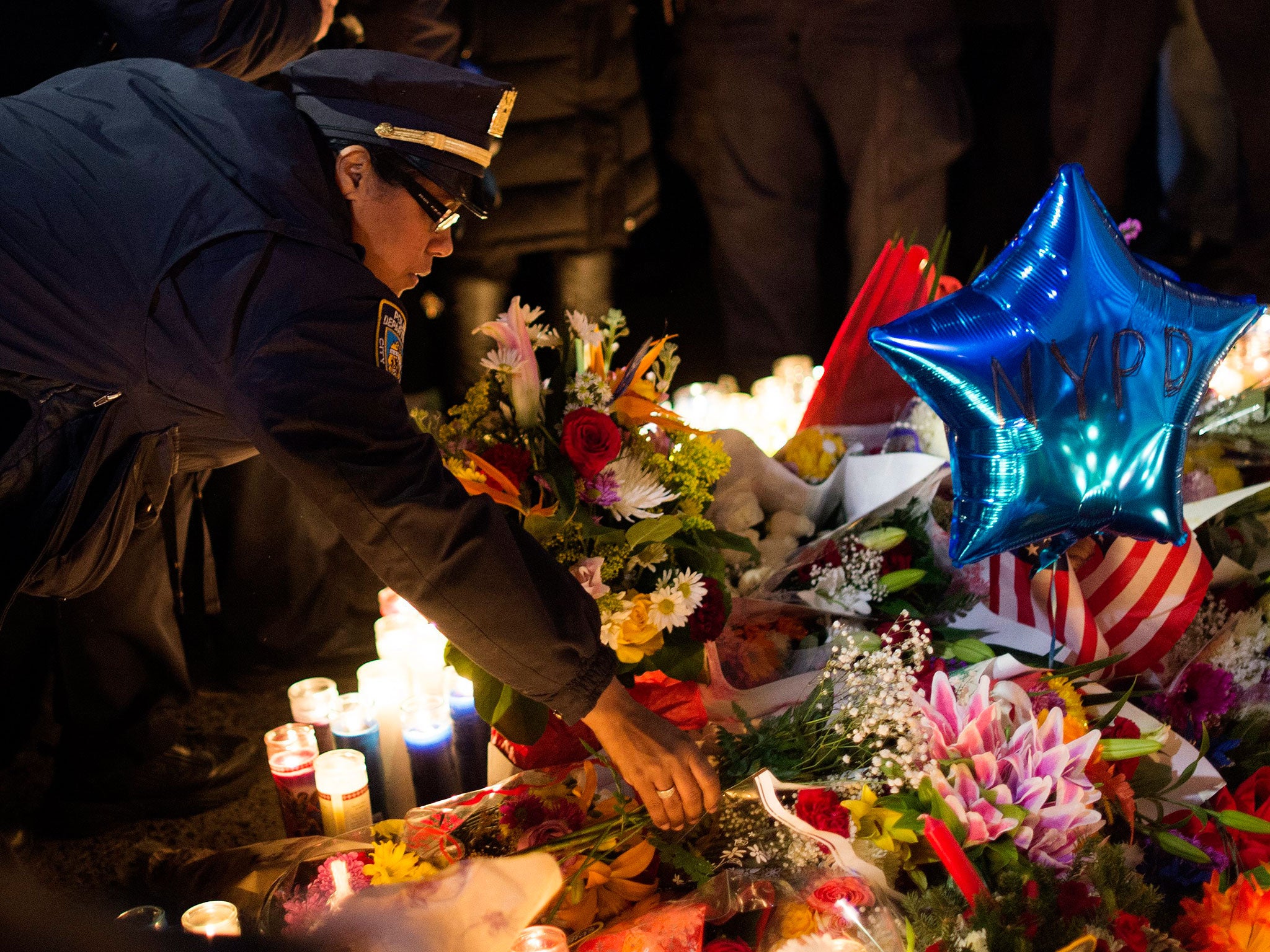 A police officer places flowers at a memorial for the two officers killed in Brooklyn, New York
