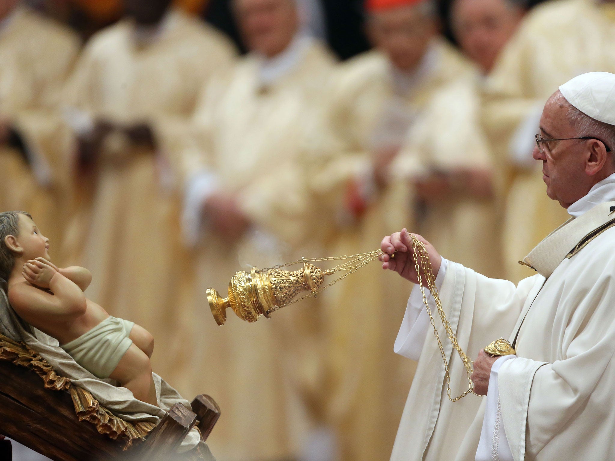 Pope Francis kisses incense the unveiled baby Jesus during a Christmas Eve mass at St Peter's Basilica to mark the nativity of Jesus Christ, on 24 December, 2014