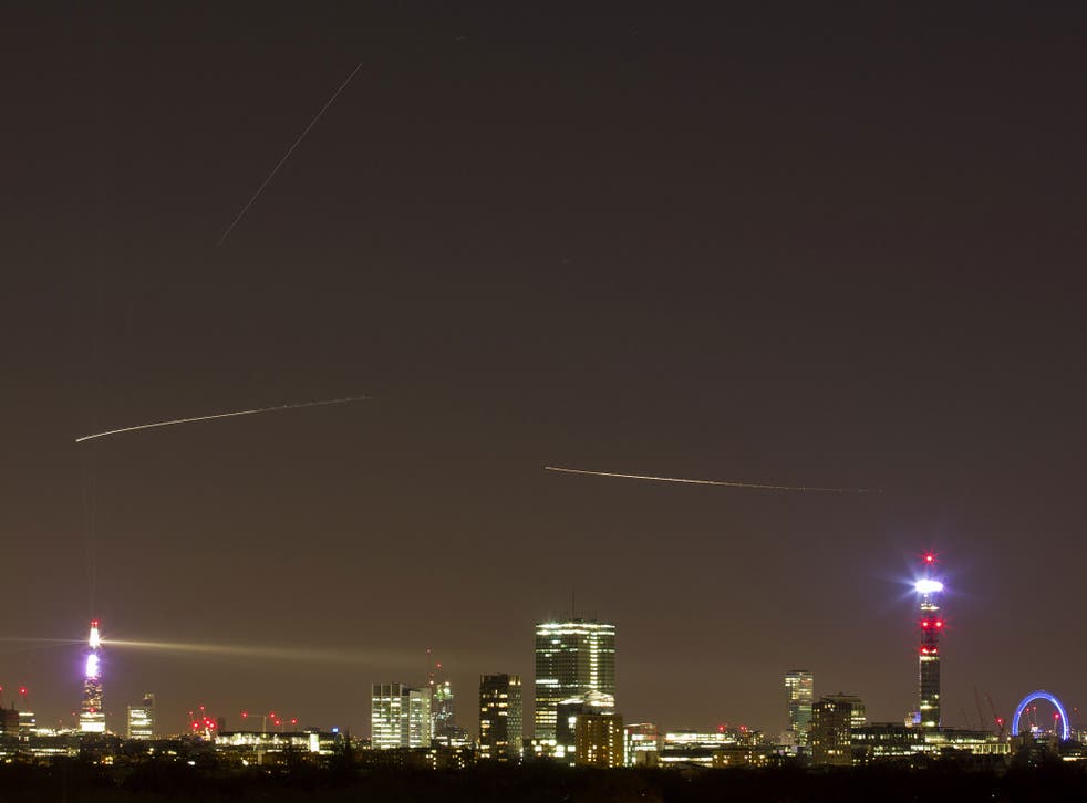 The path of The International Space Station (top straight line) is seen from central London on December 24, 2014. The trails of two aircraft on their way to Heathrow are seen below