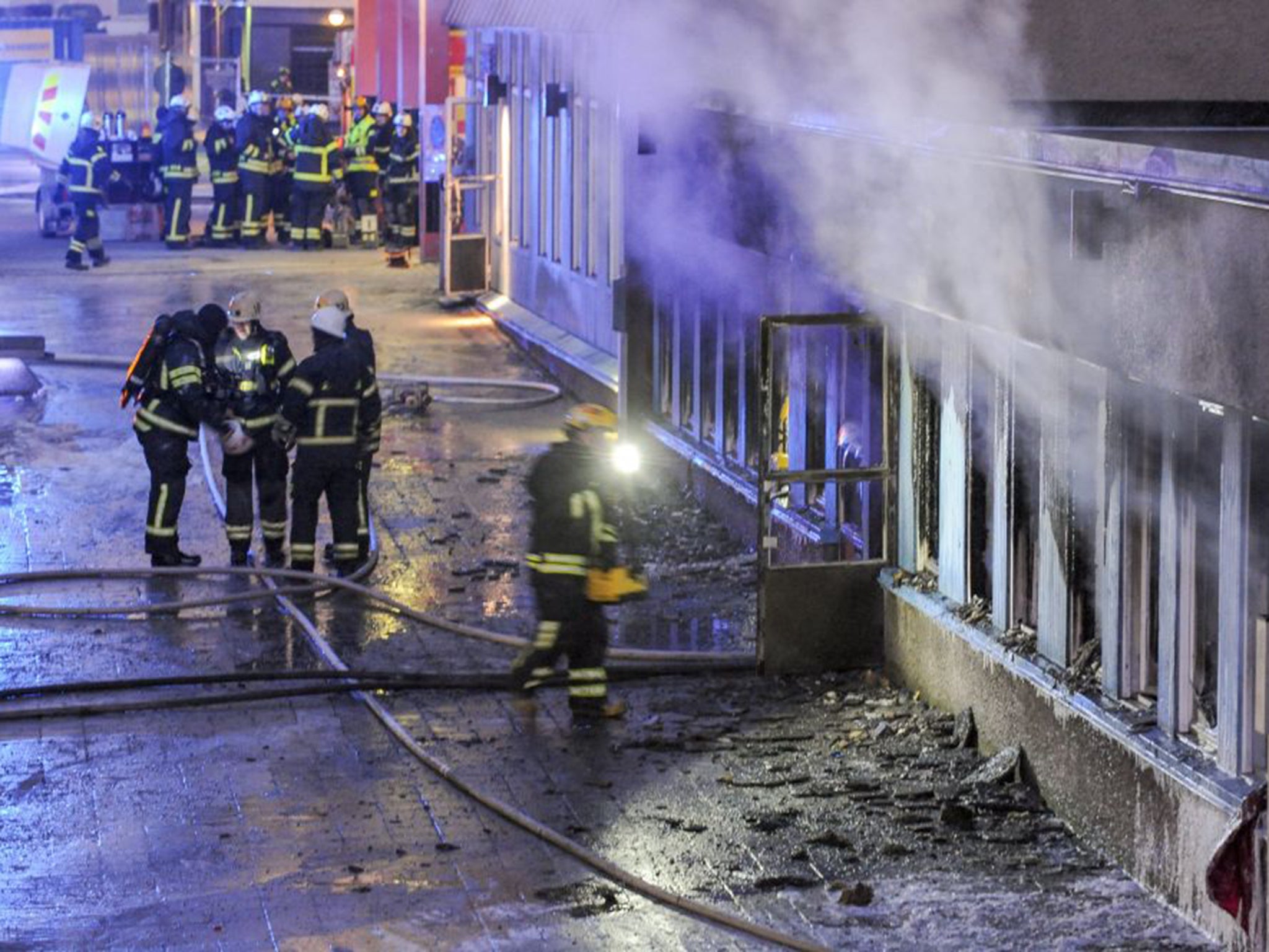 Firemen working to put out the blaze at the mosque in Eskilstuna, Sweden; five of the twenty at prayer inside were taken to hospital after inhaling smoke