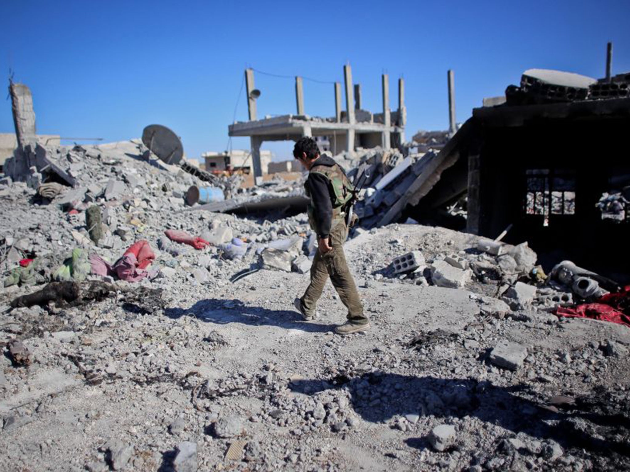 A Kurdish fighter walking past destroyed homes in Kobani Ahmed