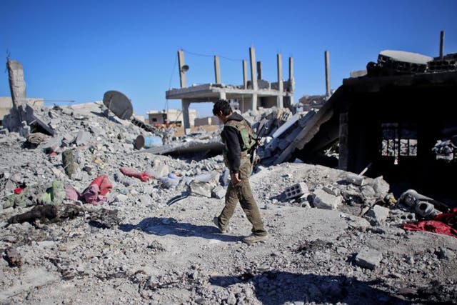 A Kurdish fighter walking past destroyed  homes in Kobani  Ahmed