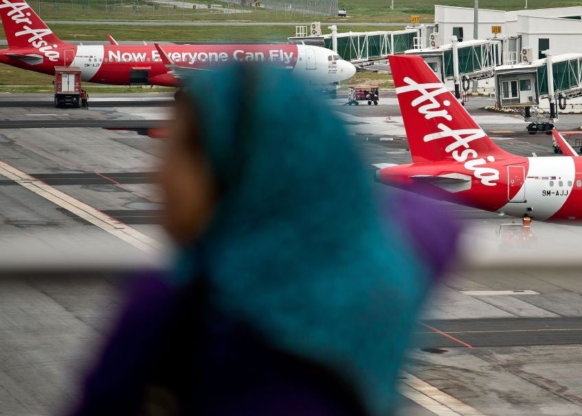 A Malaysian woman watches AirAsia Airbus A320 airplanes parked on the tarmac at the low-cost carrier Kuala Lumpur International Airport 2 (KLIA2) in Sepang on 28 December 2014