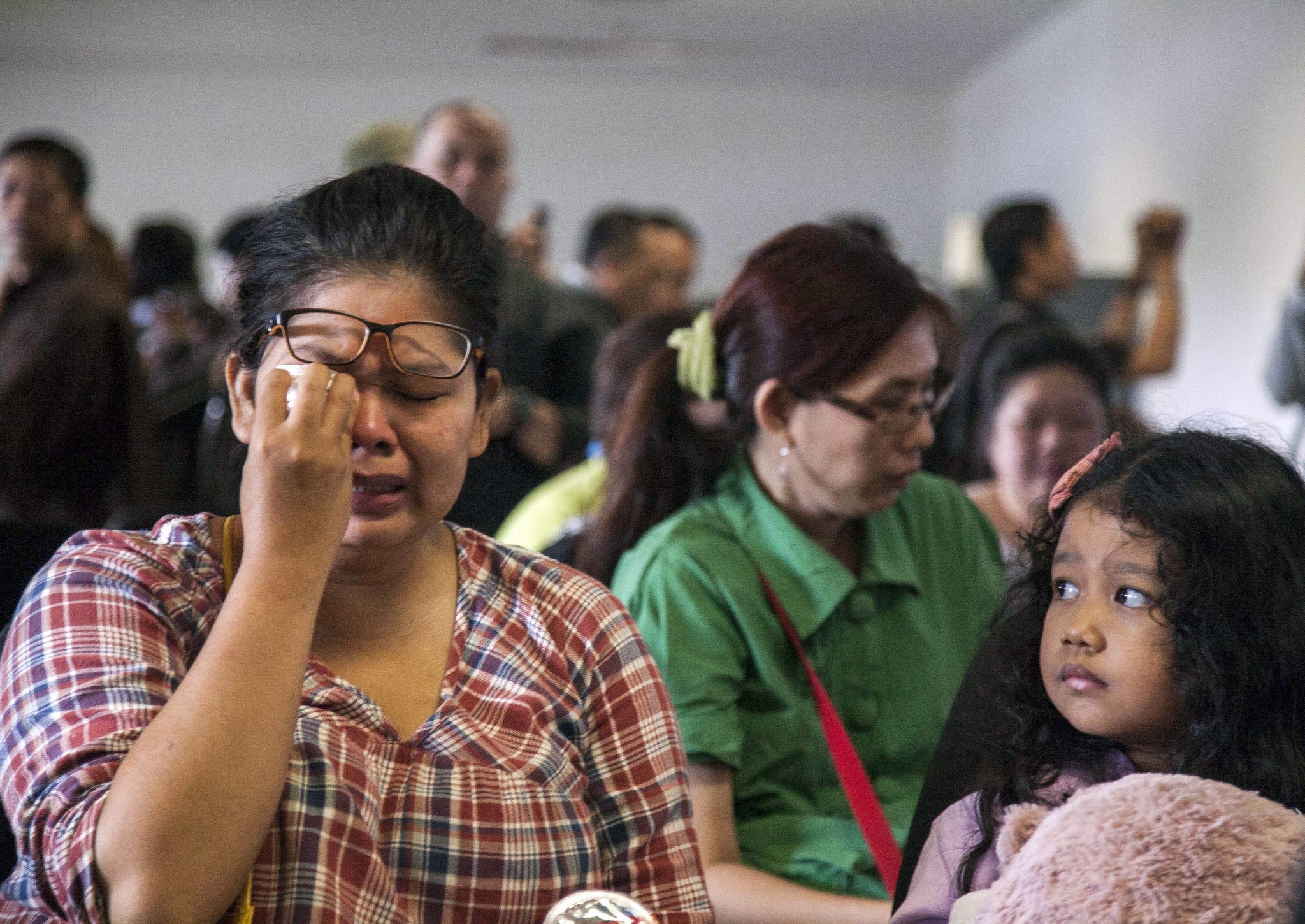 Relatives cry as they wait for news from the missing Air Asia plane at Juanda Airport, Surabaya, Indonesia
