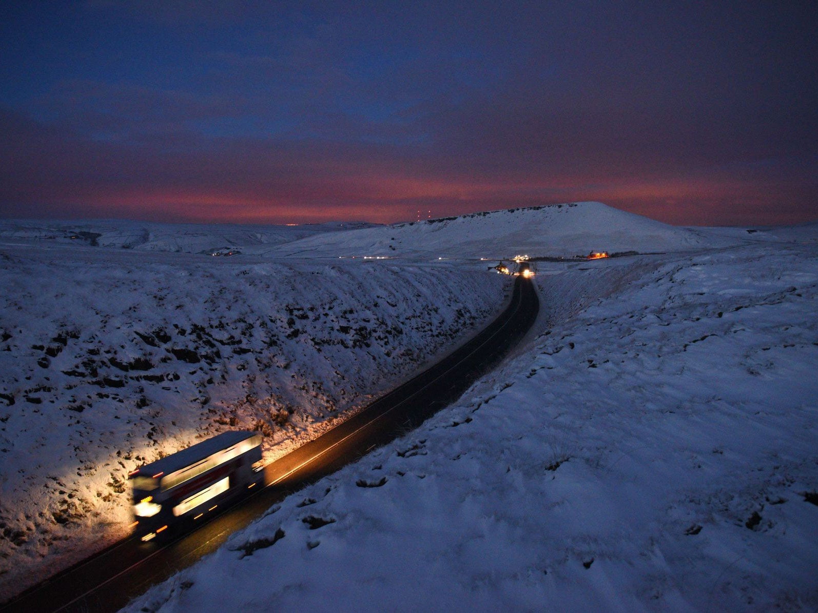 A double-decker bus travels over Standedge between snow-covered fields at dusk near the village of Diggle, northern England, on December 27 2014