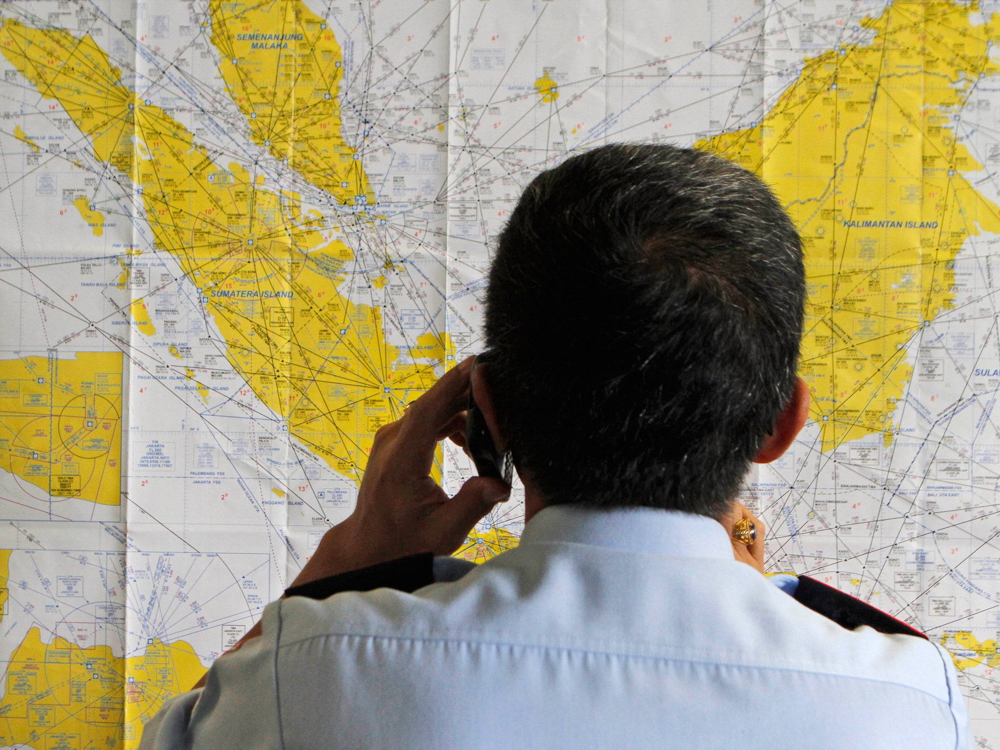 An airport official checks a map at the crisis centre set up by local authorities in the wake of AirAsia flight QZ8501 having gone missing