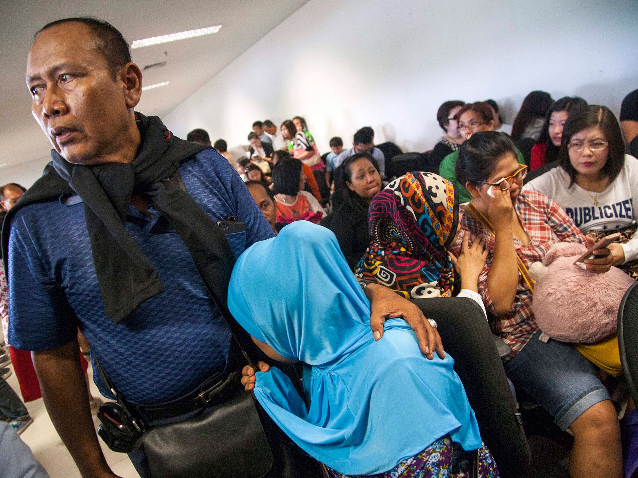 Relatives await news of the missing AirAsia flight QZ8501 at Juanda airport in Surabaya, Indonesia