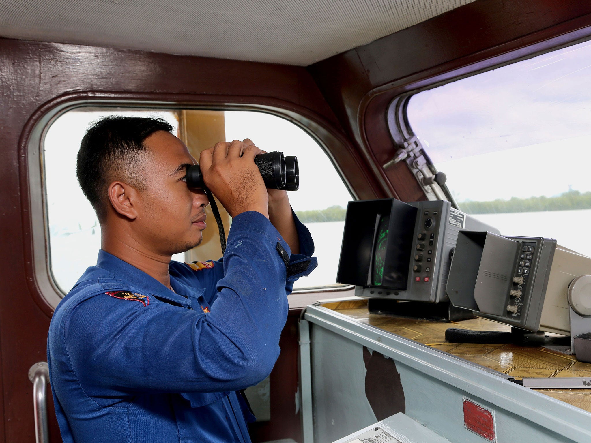 An Indonesian Marine Policeman checks his surroundings from his search and rescue crafts as he and his crew members prepare a search operation for the missing AirAsia flight QZ8501, at Pangkal Pinang port in Sumatra Island