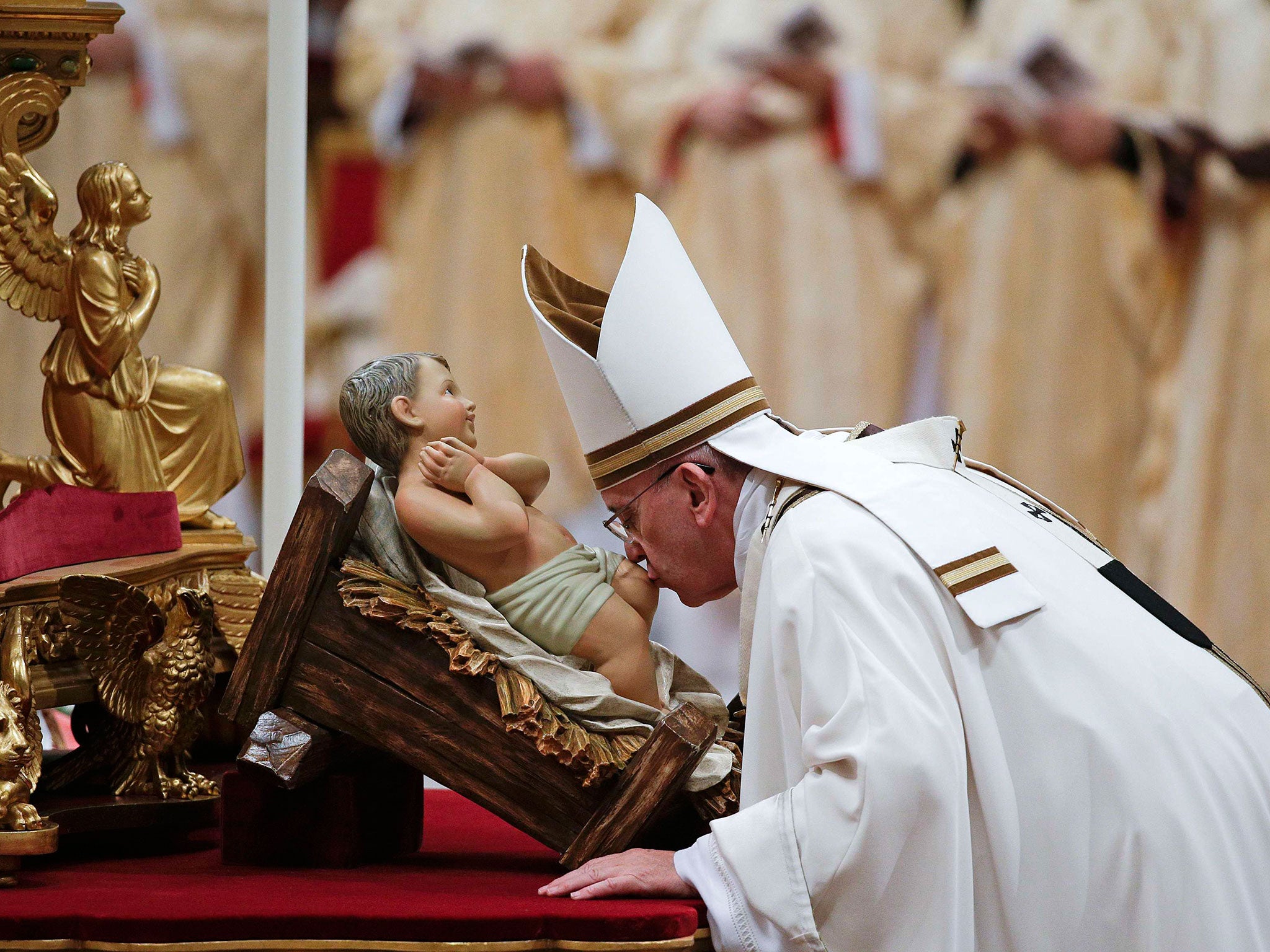 Pope Francis kisses the statue of baby Jesus as he arrives to lead the Christmas night mass in Saint Peter's Basilica at the Vatican
