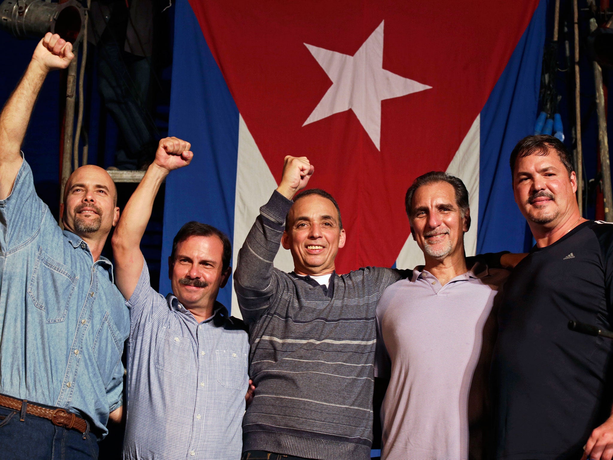 The so-called "Cuban Five" (L-R) Gerardo Hernandez, Fernando Gonzalez, Antonio Guerrero, Rene Gonzalez and Ramon Labanino, who had been jailed in the United States for spying on anti-Castro exiles in Florida, wave to the crowd in front of a Cuban flag during a concert in Havana