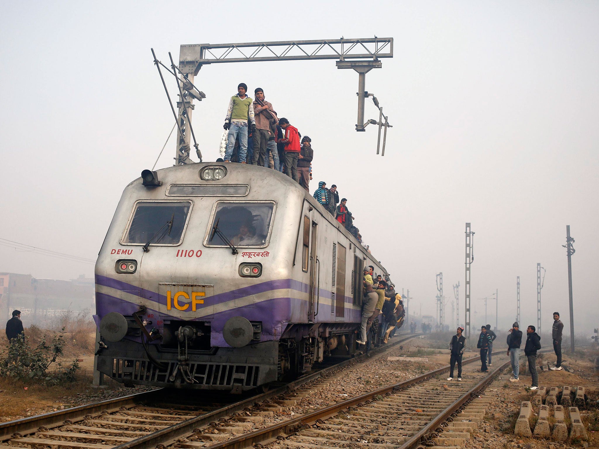 Passengers crowd atop a train as they travel on a cold winter morning at a railway station in Ghaziabad on the outskirts of New Delhi