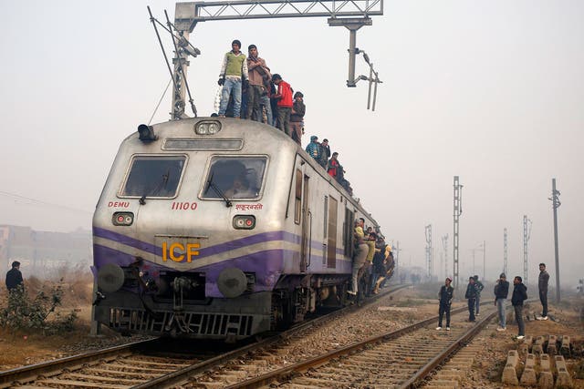 Passengers crowd atop a train as they travel on a cold winter morning at a railway station in Ghaziabad on the outskirts of New Delhi 