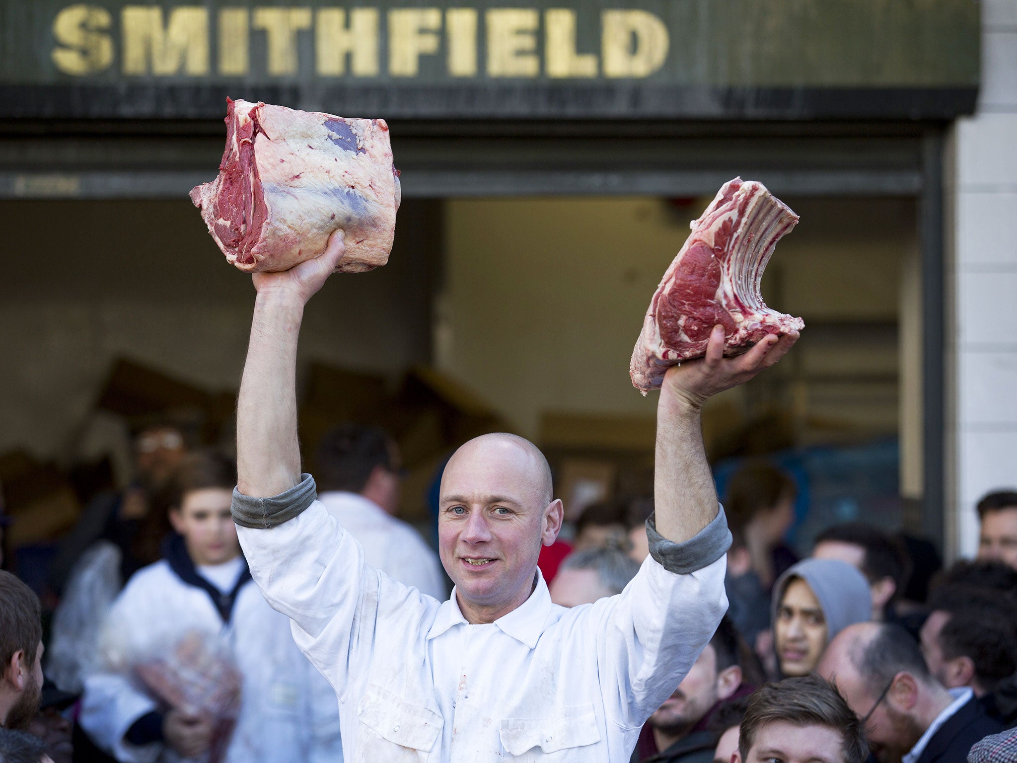 A butcher holds meat to sell during the annual Christmas Eve auction at Smithfield Market in central London