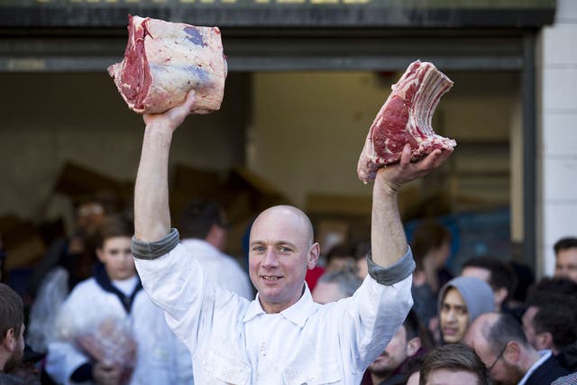 A butcher holds meat to sell during the annual Christmas Eve auction at Smithfield Market in central London 