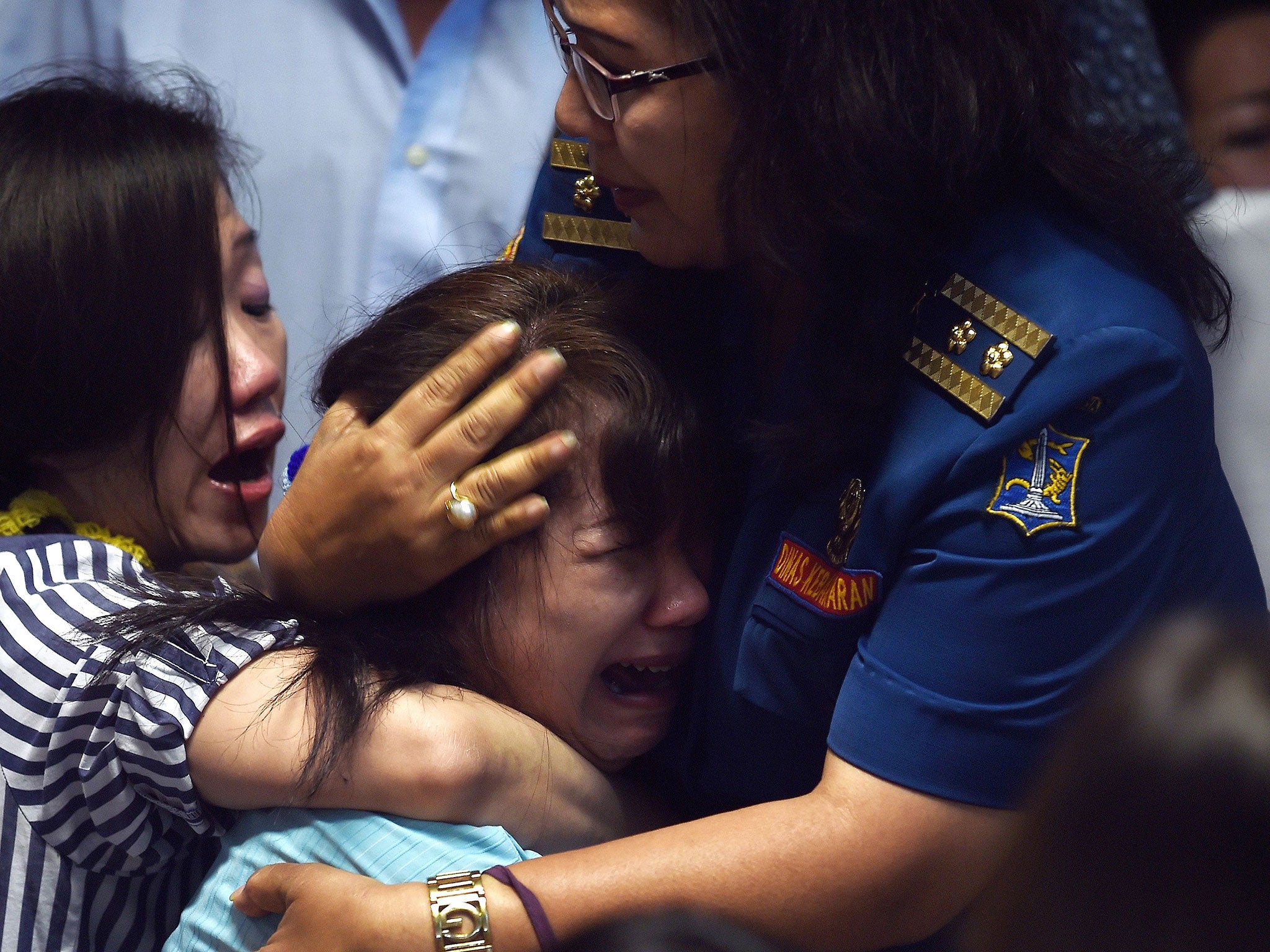 Family members of passengers onboard the missing Malaysian air carrier AirAsia flight QZ8501 react after watching news reports showing an unidentified body floating in the Java sea, inside the crisis-centre set up at Juanda International Airport in Suraba
