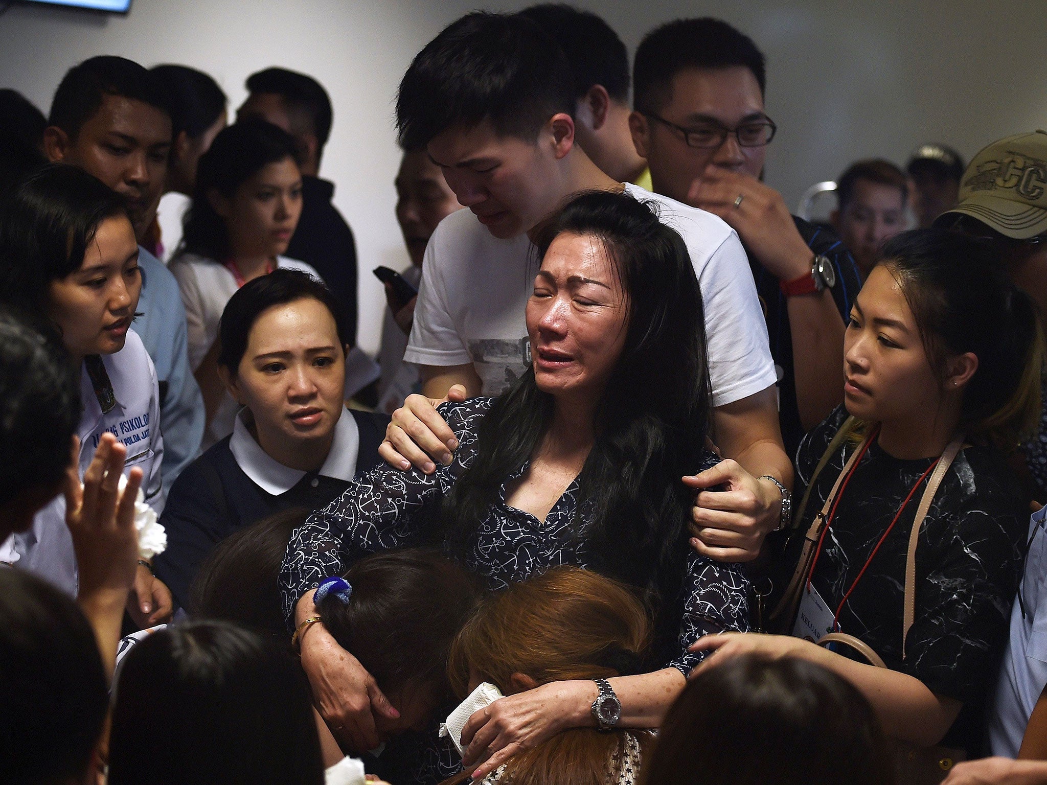 Family members of passengers onboard the missing Malaysian air carrier AirAsia flight QZ8501 react after watching news reports showing an unidentified body floating in the Java sea, inside the crisis-centre set up at Juanda International Airport in Surabaya