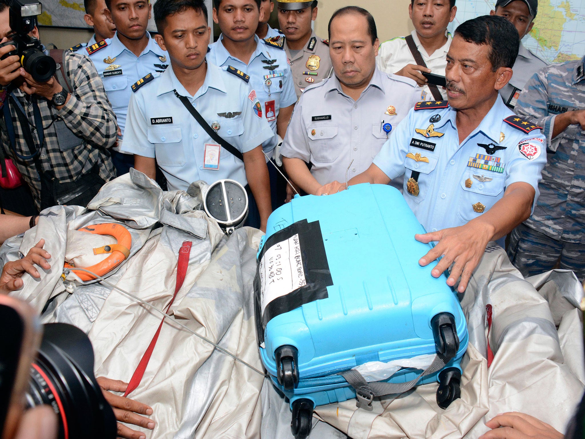 Commander of 1st Indonesian Air Force Operational Command Rear Marshall Dwi Putranto, right, shows airplane parts and a suitcase found floating on the water near the site where AirAsia Flight 8501 disappeared, during a press conference at the airbase in Pangkalan Bun, Central Borneo, Indonesia