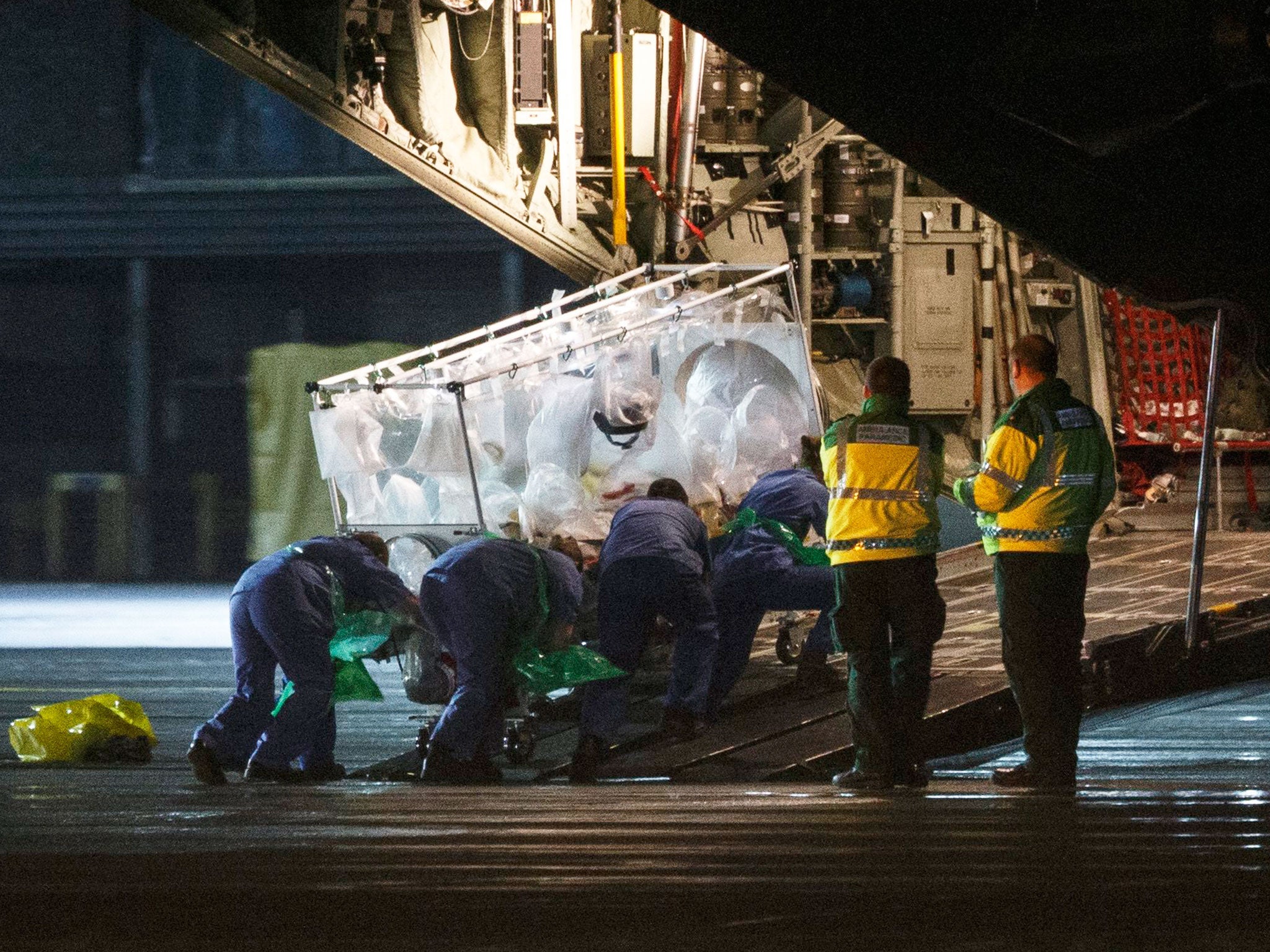 Medical personnel load an isolation bed with a woman diagnosed with Ebola onto a Hercules transport plane on the airport in Glasgow, Scotland