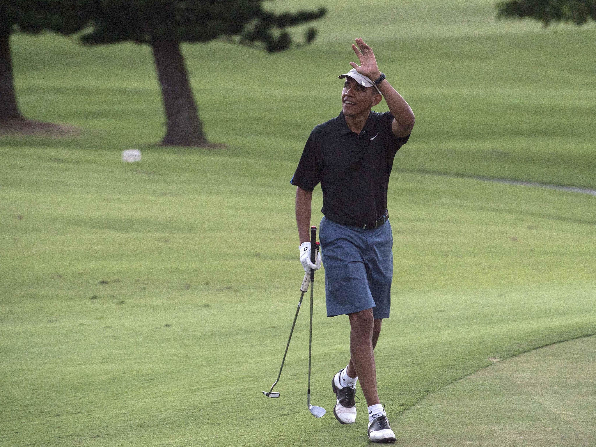 Obama waves to onlookers as he plays golf at the Mid-Pacific Country Club in Kailua on 30 December, 2014