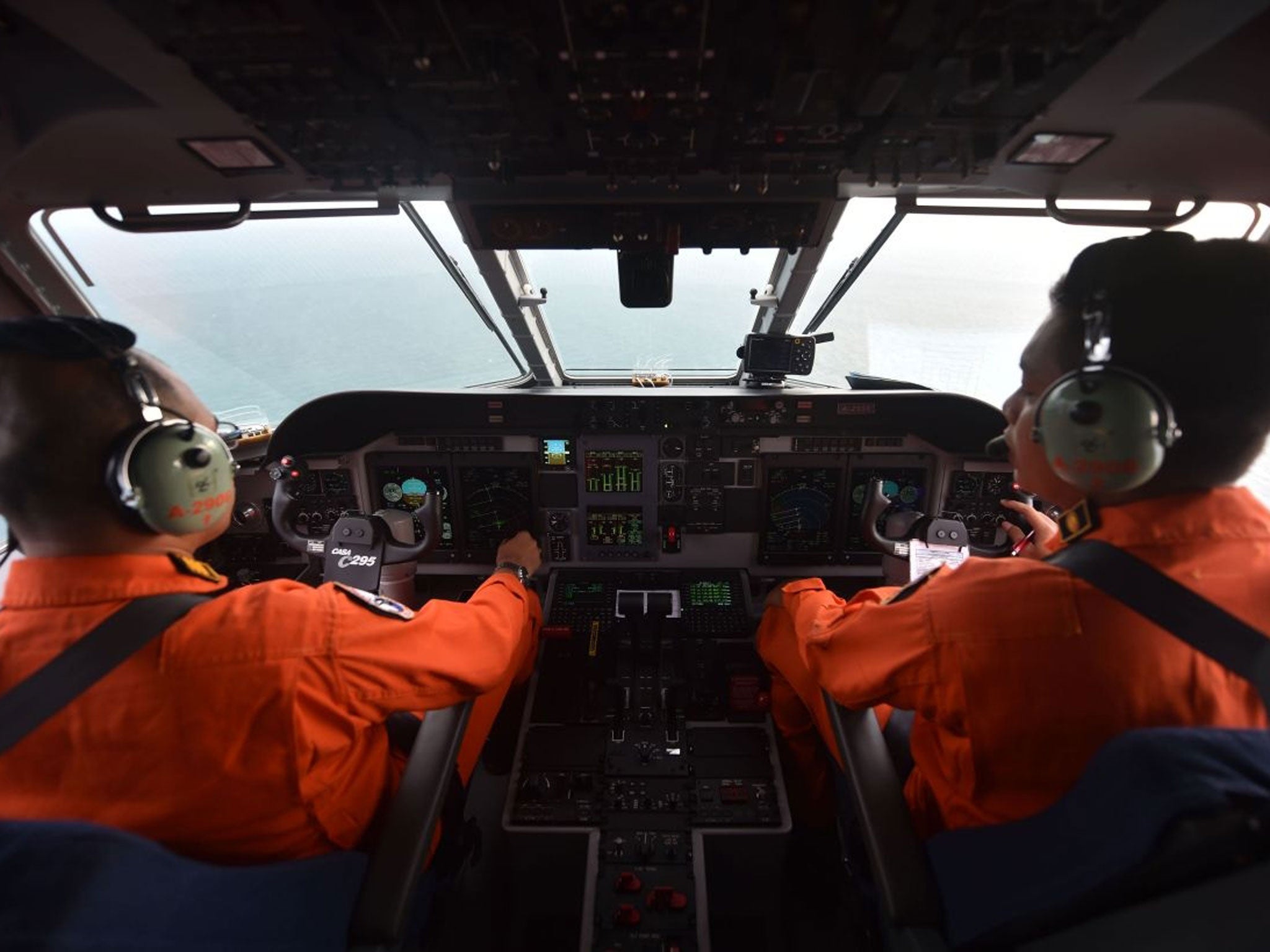 Pilot and co-pilot of the Indonesian air force keep a look out during search and rescue operations for the missing AirAsia flight QZ8501