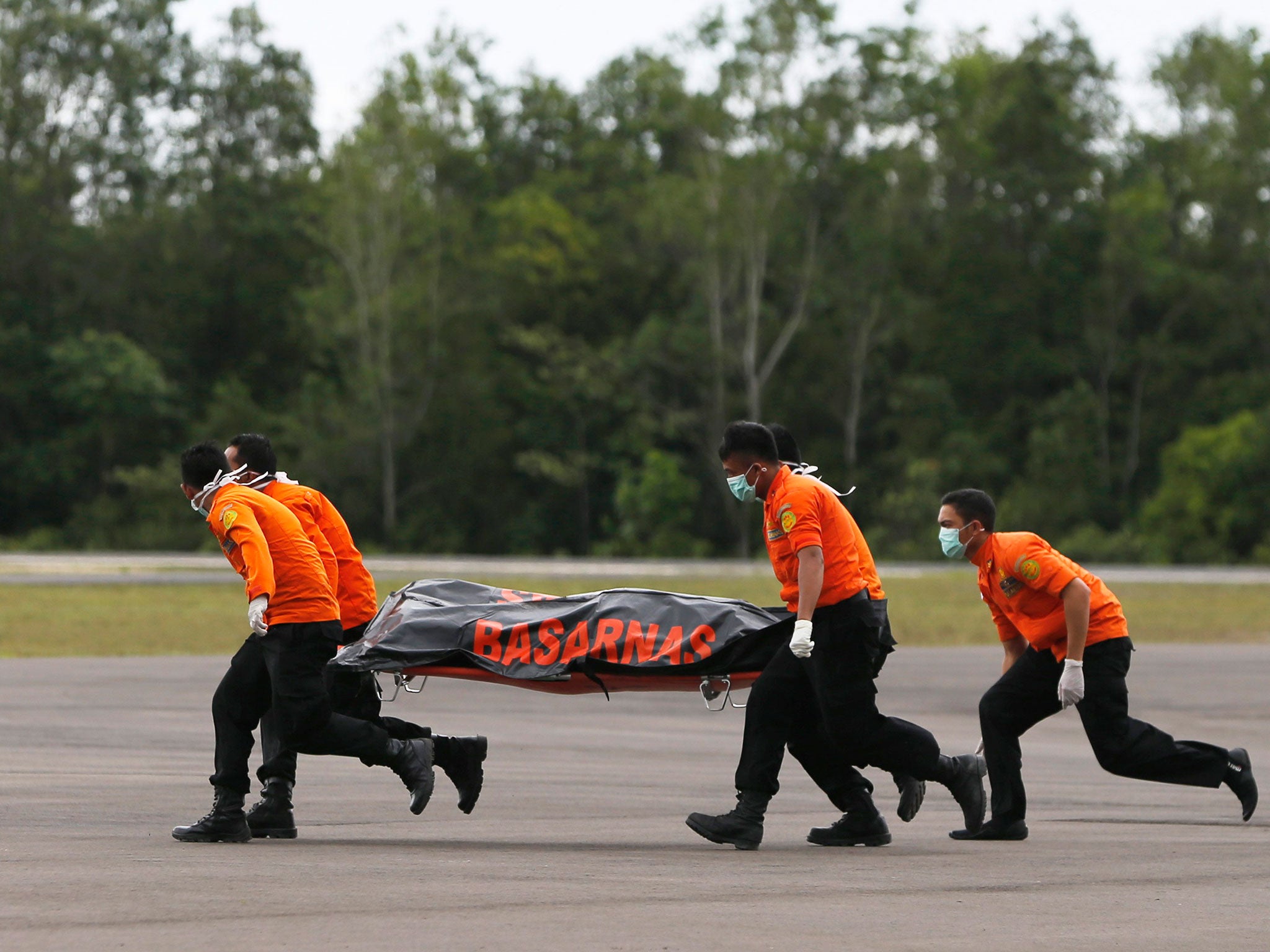 Search and rescue team members carry the dead body of a passenger onboard AirAsia flight QZ8501 in Indonesia