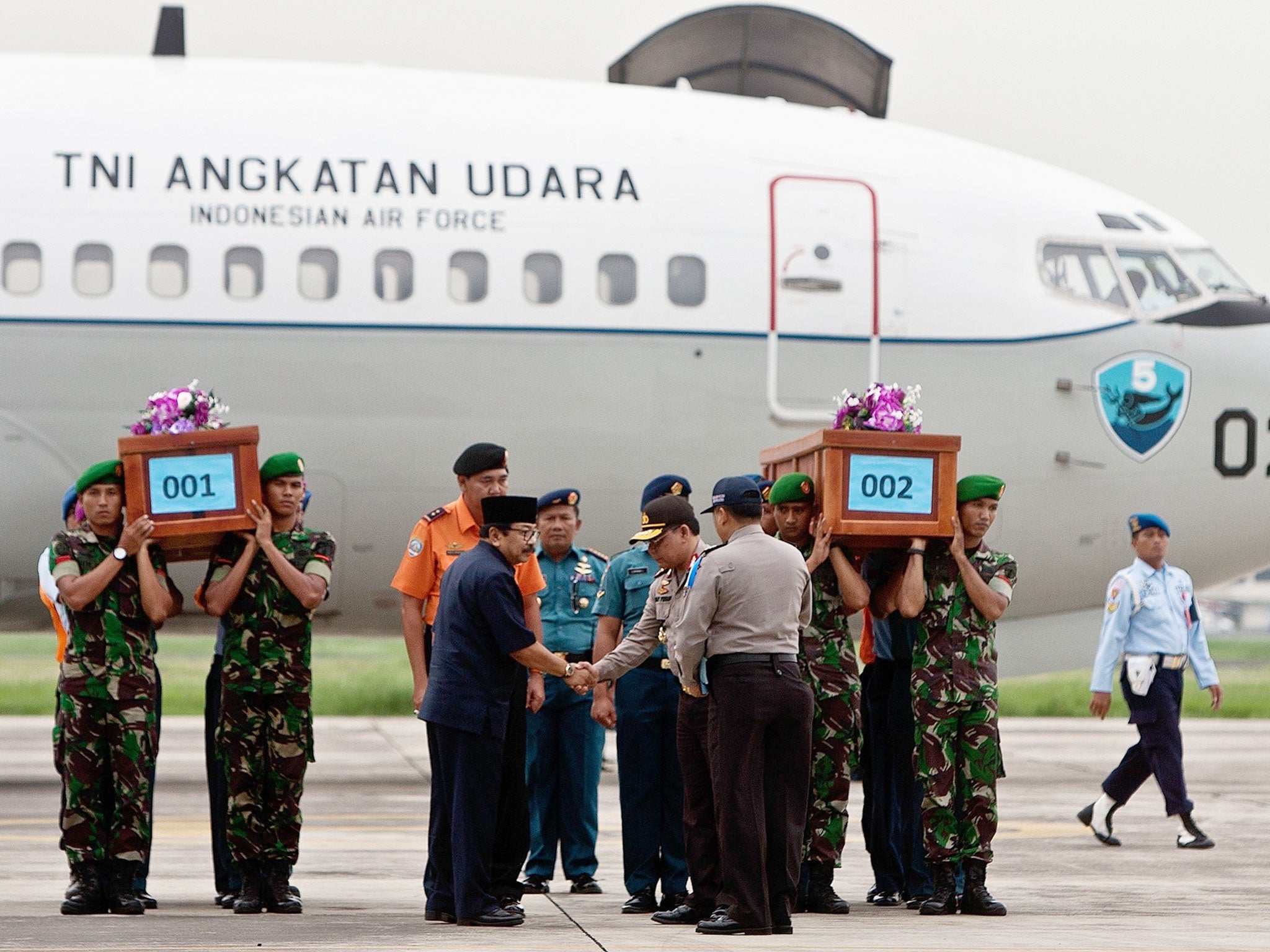 Indonesian military personnel carry coffins of victims recovered from the ill-fated Malaysian air carrier AirAsia flight QZ8501