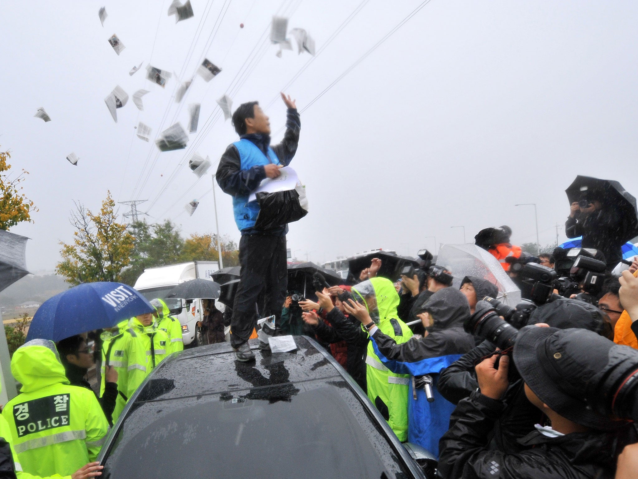 Park Sang-hak scatters anti-Pyongyang leaflets as police block a rally in October 2012