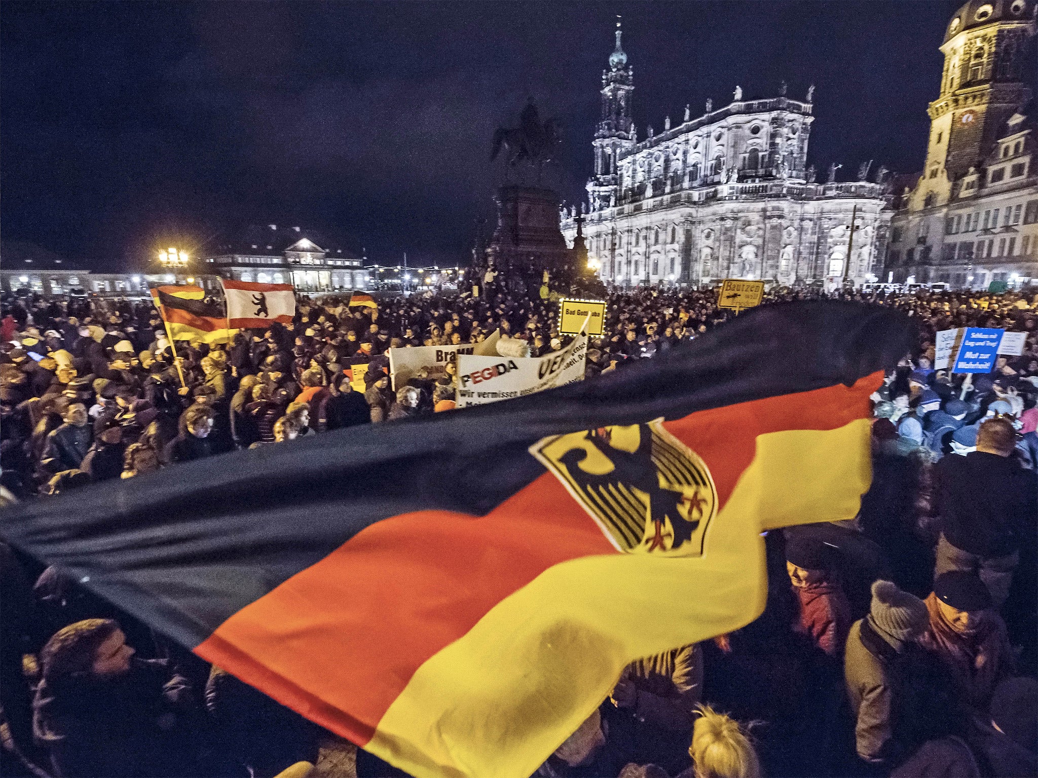 Supporters at a Pegida rally hold German flags and lights during a demonstration held each week for the past 10 weeks in front of the Dresden Cathedral in eastern Germany