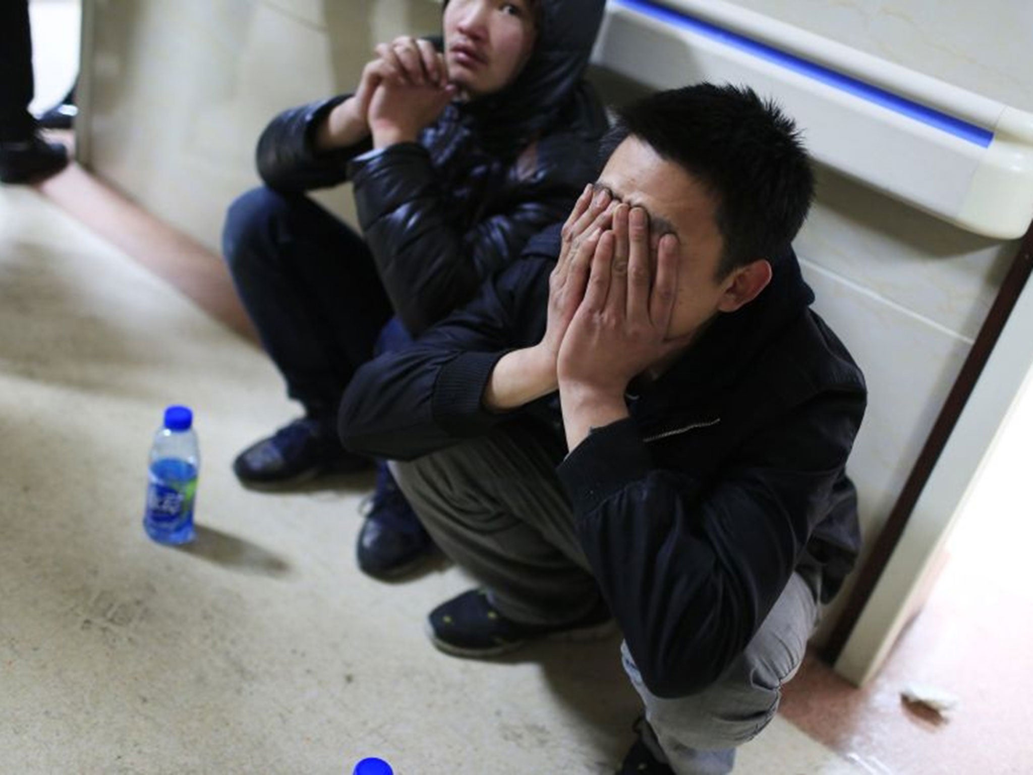A friend of a victim covers his face as he waits outside a hospital where injured people of a stampede incident are treated, in Shanghai