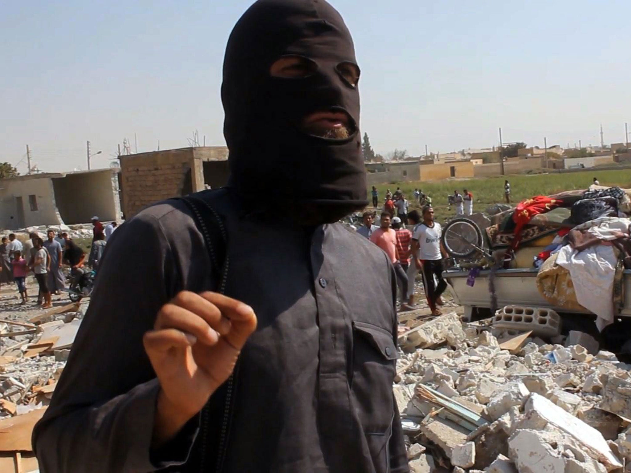 An Isis jihadist pictured standing on the rubble of houses after a Syrian warplane was reportedly shot down by Isis militants over the Syrian town of Raqa in September, 2014