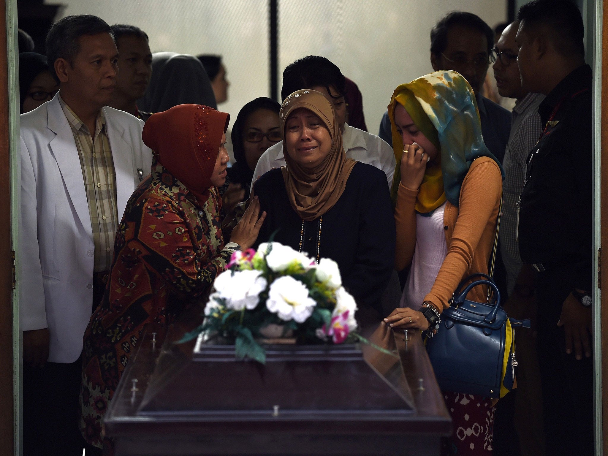 Family members including the mother (C) of Hayati Lutfiah Hamid, receive her remains at the police hospital in Surabaya