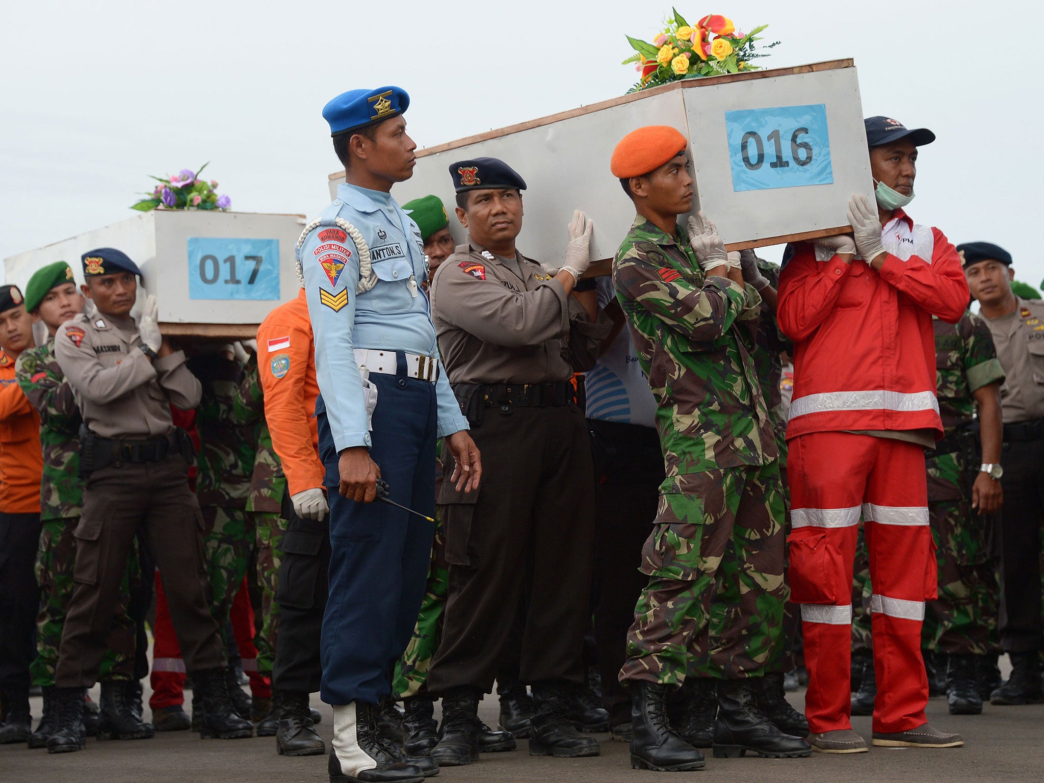 Indonesian officers carry coffins with the remains of passengers of the AirAsia flight QZ8501
