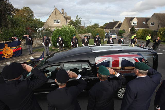 Retired Royal Marine personnel salute as a hearse passes through the village of Brize Norton in 2011 (Getty)